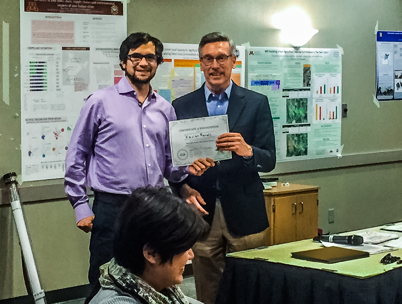 Xavi Fonoll of the University of Michigan accepts the award for top poster in physical modeling group from Bob Johns, a senior fellow at the Humphrey School of Public Affairs and strategy adviser to the network.