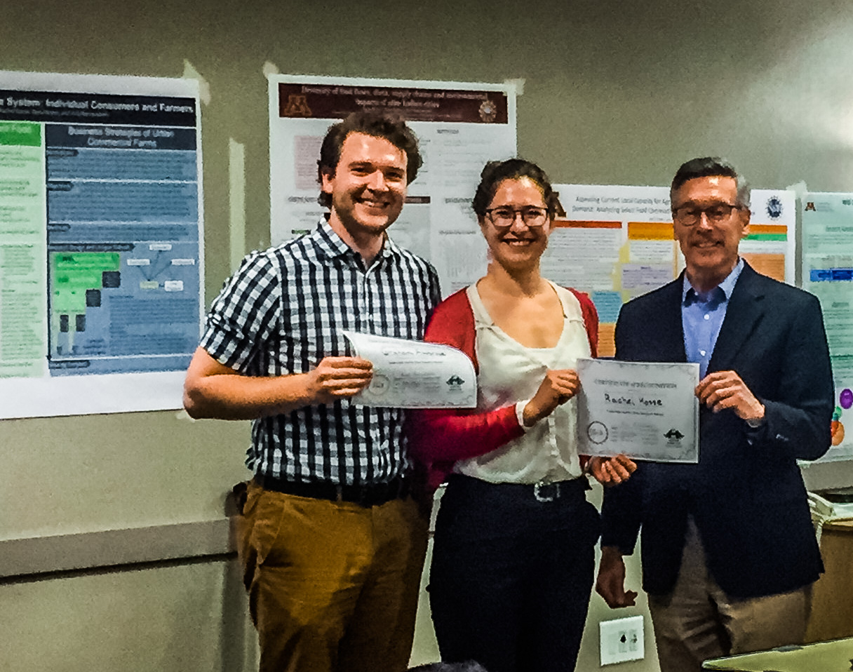 Graham Ambrose and Rachel Kossee of the University of Minnesota accept the award for top poster in the social actors and governance group from Bob Johns, senior fellow at the Humphrey School of Public Affairs and strategy adviser to the network.