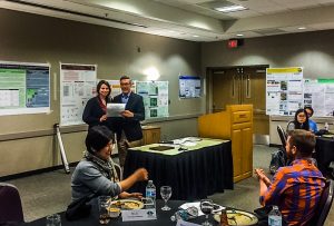 Lara Clark of the University of Washington accepts the award for top poster in the theme 1 group from Bob Johns, senior fellow at the Humphrey School of Public Affairs and strategy adviser to the network. 