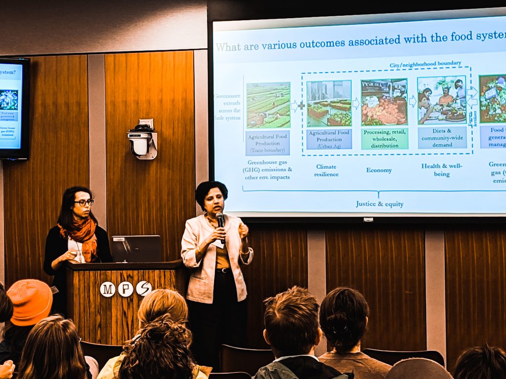 Two researchers present research to a community forum audience. 